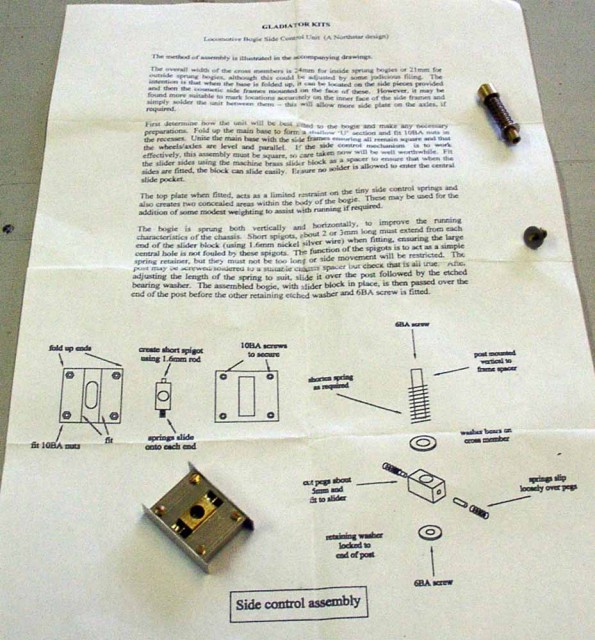 Le « side control unit » de Gladiator dont la dénomination est un faux ami.<br />Il s’agit d’un module de guidage / rappel du bogie, destiné à être incorporé dans un bogie de locomotive. Avec ce module en maillechort et laiton, à assembler pour l'essentiel par soudure :<br />- la locomotive est guidée dans les courbes par son bogie, comme en réalité, les deux ressorts opposés ramènent constamment le bogie vers son point milieu, évitant un trop grand déport du châssis par rapport à la courbe ;<br />- la colonnette équipée d’un ressort d’appui plaque le bogie sur la voie ;<br />- le montage du module dans le bogie abaisse le niveau du pivot de bogie et réfrène la tendance au soulèvement des roues extérieures du bogie dans les courbes. Accès au site Gladiator.