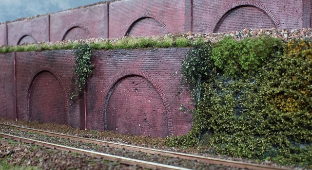 Cette photo (de Philippe) de son réseau montre la mise en place de ces murs. En fait il y en a plusieurs mètres, ce qui évidemment justifiait la création d'un modèle maître gravé et du moule. Philippe souhaitait un aspect vieux murs marqués par le temps et les intempéries. Ces murs sont en fond de décor, pas au premier plan, et les imperfections du moulage simulent très bien l'usure de la brique.