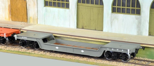 Nouveauté chez Darstead cette année, disponible à Telford. Ce modèle et les deux en dessous sont trois décorations du même wagon surbaissé à bogies. Le gris et le orange sont à Pierre M., et le brun à Patrick S.<br /><br />Ils sont pratiquement à l’échelle. Conçus dans le style "tin-plate" mais dont la superstructure est en matière plastique bien moulée, les roues sont de la marque réputée Slater's, et le plancher en adhésif imprimé. C'est un wagon réaliste aux multiples marquages, vendu à  £69, environ (change) 75 à 80 €. Réalisation assez fine. Disons-le tout de suite, si Darstead offre une douzaine de livrées, c’est la même caisse qui est utilisée, pour toutes, sacrifiant les détails qui distinguaient les différentes versions et constructeurs. mais nous ne somme qu’à  moins de 80 € pour un modèle tout monté. Il faut savoir raison garder ! Le résultat quoique simplifié sans doute laisse un véhicule loin d’être ridicule. à noter que la maison Hatton's lance la souscription d’un wagons surbaissé d’un type un peu plus récent pour une valeur de £85, avec une douzaine de livrées également des années 1925 à 1970…