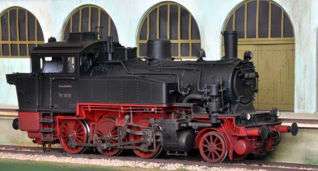 Texte de François Bozon : La BR 91 (ex T9.3 prussienne) de Hübner (Eurotrain) sortie à la fin des années 70 est à ma connaissance le premier modèle de petite machine disponible en finescale « haut de gamme », avec la particularité d’avoir des caisses à eau en métal injecté alors que le reste de la machine est en laiton ! Il fut décliné en versions DB / DRG / KPEV ainsi que SNCF et SNCB et taillé pour une exploitation universelle puisqu’il était officiellement apte au franchissement de courbes de 800 mm de rayon.<br /><br />Le modèle présenté est donc une BR 91 en version DB post 1957 (troisième phare), reprise pour être conforme à l’original d’un point de vue esthétique : caisses à eaux complétées de couvercles de soutes et de crochets de levage, lanterneau réduit, cloche débarrassée de son piédestal, nouvelle sablière (pas un simple cube) et nouvelle pompe à air (à l’échelle et non rabougrie), essieu porteur doté de roues fines avec un gros moyeu. A cela s’ajoute une nouvelle mécanique, la digitalisation/sonorisation et la patine.<br /><br />Avec son essieu porteur à l’avant, cette loco tender est utilisable sans difficulté en tête de trains voyageurs composés de voitures à portières latérales (Lenz) ou à plateformes (Hobby Teknik) comme de trains de marchandises sur de petites lignes et donc idéale pour un réseau en chambre !