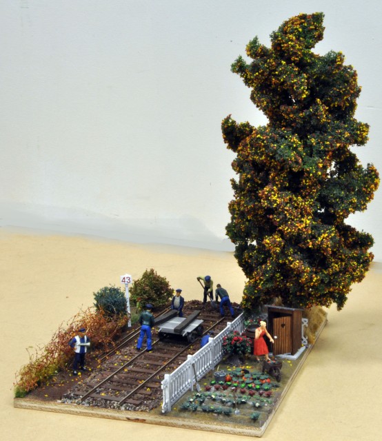 DIORAMA : réalisé sur un A4 pour être présenté à TRAINSMANIA à Lille, en mai prochain, ce petit diorama est animé par un remplacement de traverse, ayant nécessité la dépose du rail. Un lorry a permis d’approcher les traverses neuves, en attendant l'évacuation des vieilles. Pendant ce temps la garde barrière travaille dans son jardin en ce début d’automne… On peut noter la présence d’un PK 43 en impression 3D sur le module.