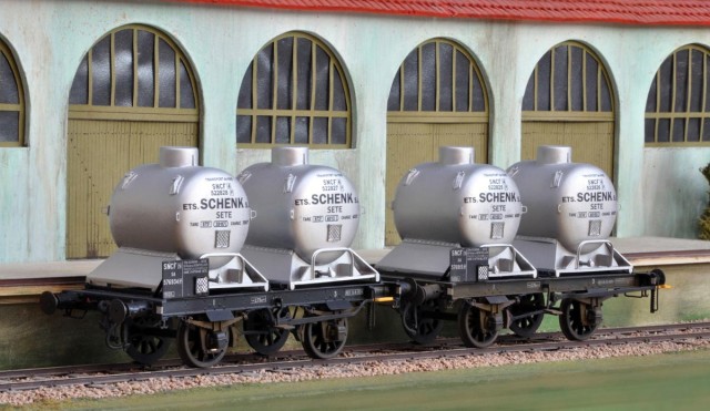 Historique :<br /><br />Les châssis de ces wagons proviennent de wagons bi-foudres du PLM. Réaménagés en 1949 ils reçoivent à demeure des containers citernes. Ils assurent le transport de vin. Ils ne sont équipés que d’un antique frein d’immobilisation à levier.<br /><br />La base est un kit rassemblant les deux wagons conçu par Haxo Modele.<br /><br />Les containers ont leurs bases entièrement refaites. Leur arrimage est évoqué et semi-fonctionnel : les citernes ne tombent plus lorsque le wagon roule !<br /><br />Les casiers porte-étiquettes d’origine (wagons et containers) ont été avantageusement remplacées par des modèles de la même marque fonctionnels et très finement gravés et ajourés.<br /><br />Montage classique au fer, à la SRE et au chalumeau. Sablage, puis apprêt et peintures (Rail Color) à l’aérographe. Pose des décalques (aide des produits MicroScale), vernis (MicroScale) brillant puis mat.<br /><br />Patine (Rail Color) légère à l’aérographe, travaux fins au pinceau, et petites touches à la terre à décor.