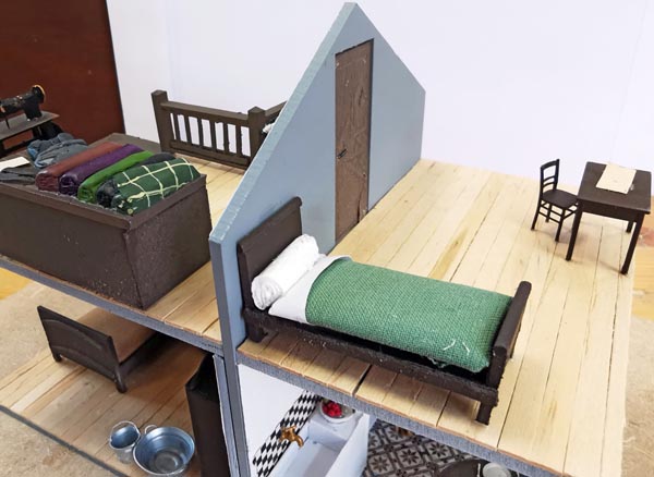 Le mobilier, la table de la cuisine, le buffet Henri II, les lits, commode et armoire normande sont en carton. Les chaises de la salle viennent de chez AUBERTRAIN. La table de la mansarde est de fabrication PREISER, ainsi que les chaises à l’étage. Le meuble de la couturière est en carton, avec le dessus tiré d’un étal de tissus de chez PLM Castaway (UK). La machine à coudre est faite maison, en carton et bois. J’ai imaginé le scriban qui pouvait sans doute servir (avec son cadran COPIRAIL) à la tenue des documents de service. Deux drapeaux (un vert et un rouge sont en fil de fer, et papier roulé autour de leur manche. Là encore, il a bien fallu faire preuve d’imagination pour trouver le matériel nécessaire au service. La règlement à l’usage des Garde-Barrières (PLM 1894) a aidé à reconstituer ce qui pouvait être nécessaire. <br />Le mari qui dort dans son fauteuil est une figurine (d’une pièce) PLM CASTAWAY.